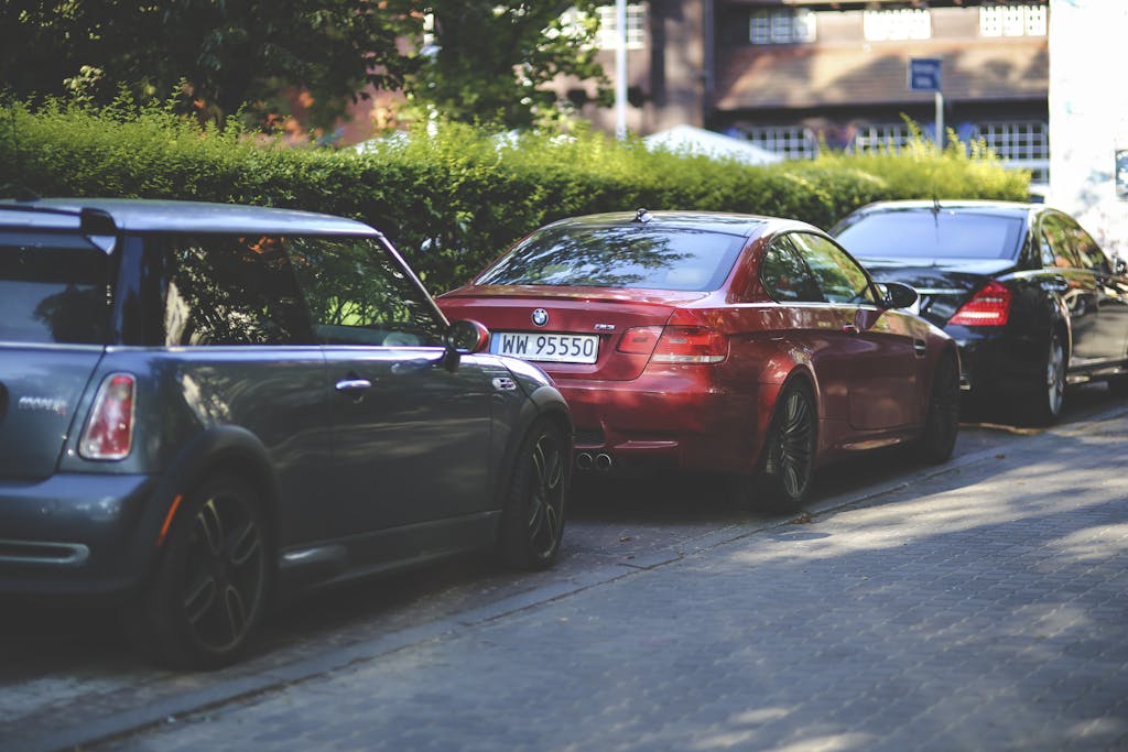 BMW M3 and Mini Cooper parked on a tree-lined street, showcasing sleek auto design.